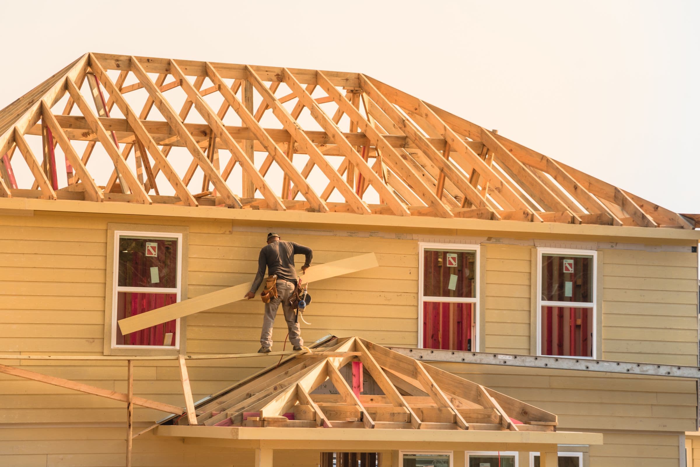 A builder working on a house at sunset