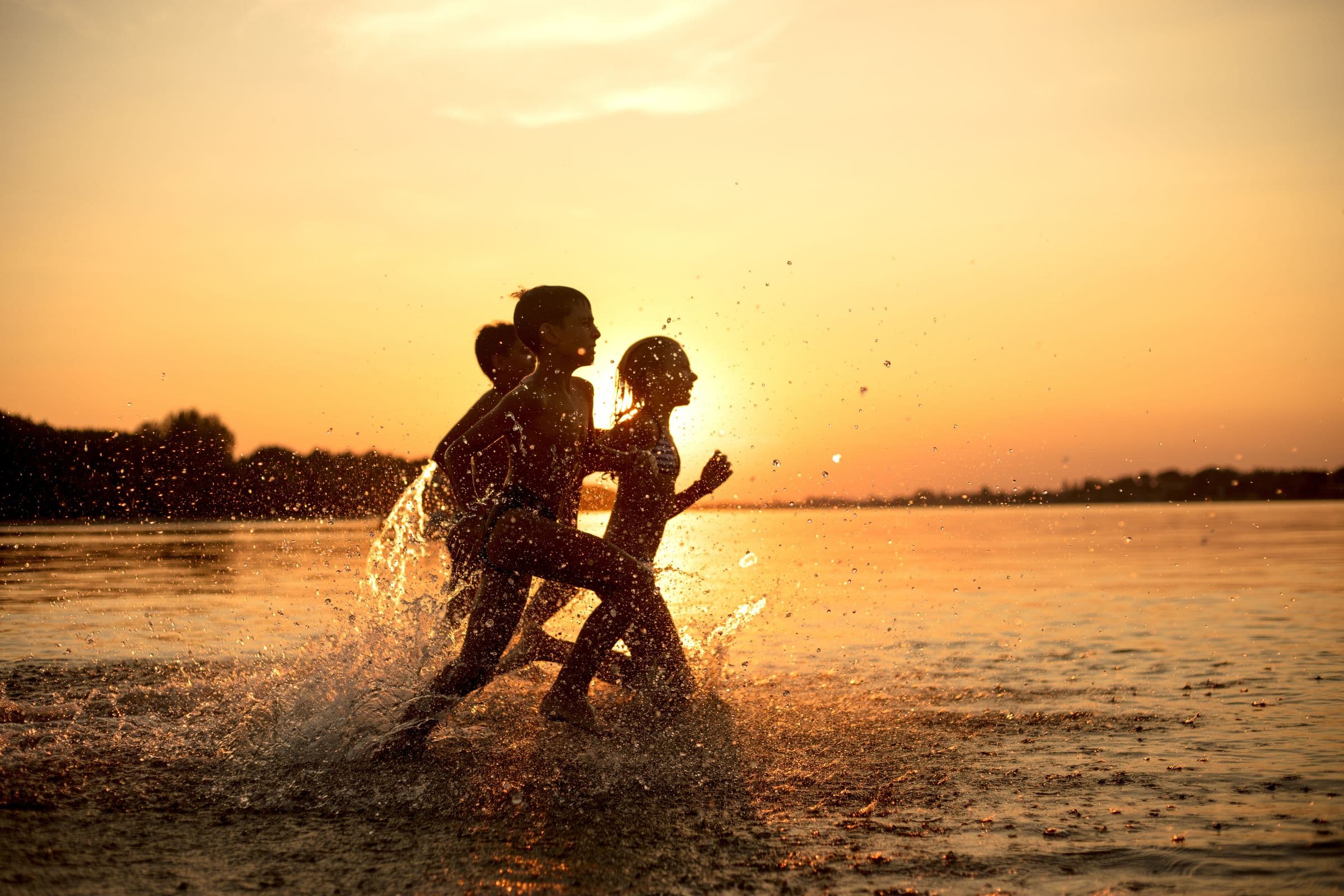 Children playing in the sea at sunset